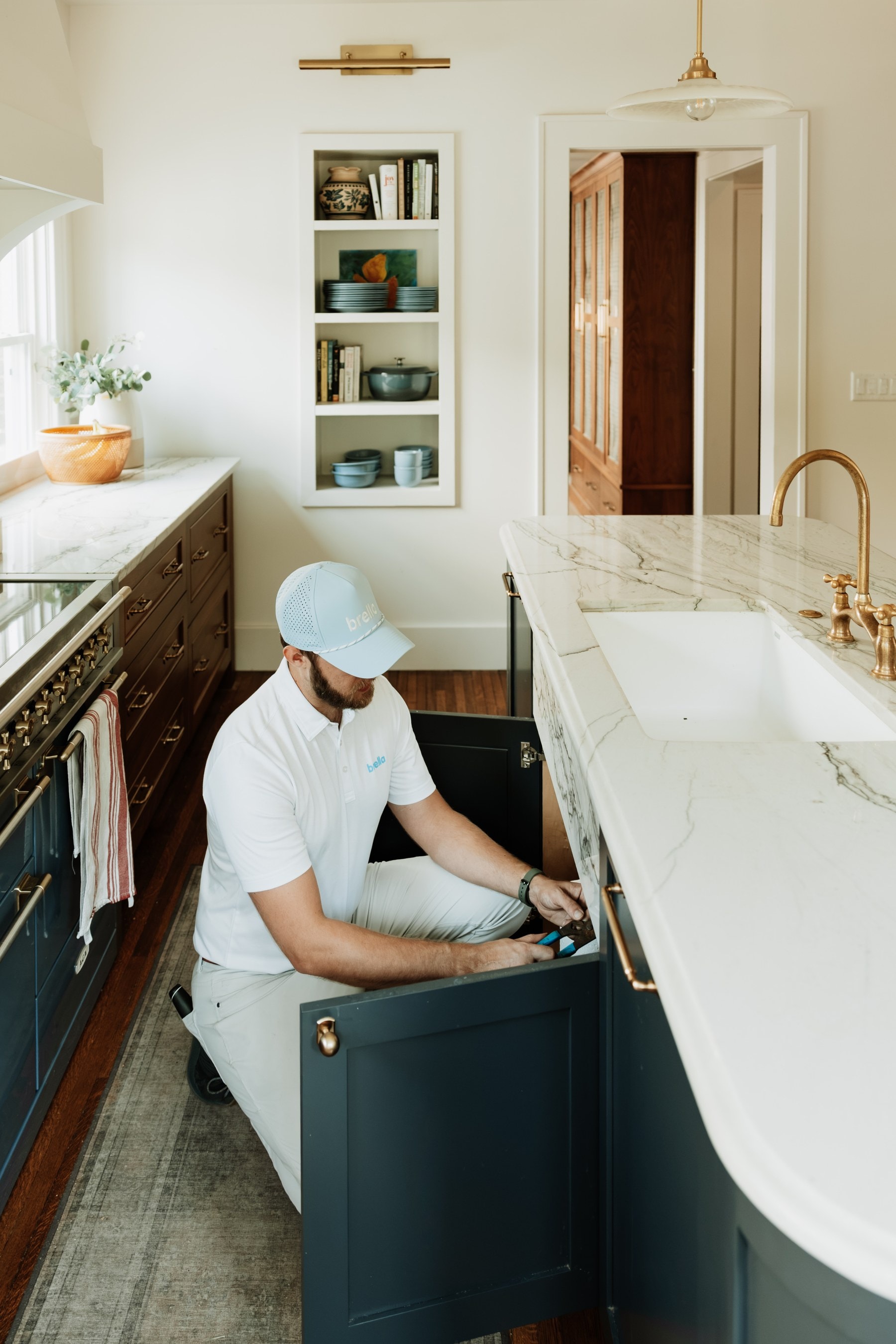 A Brella technician checking under a kitchen sink cabinet